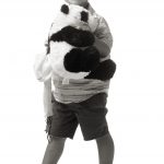 Young boy with glasses holding a plush panda bear doll