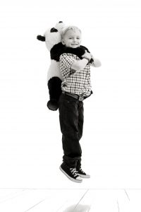 Photo of boy holding a panda bear over his shoulders